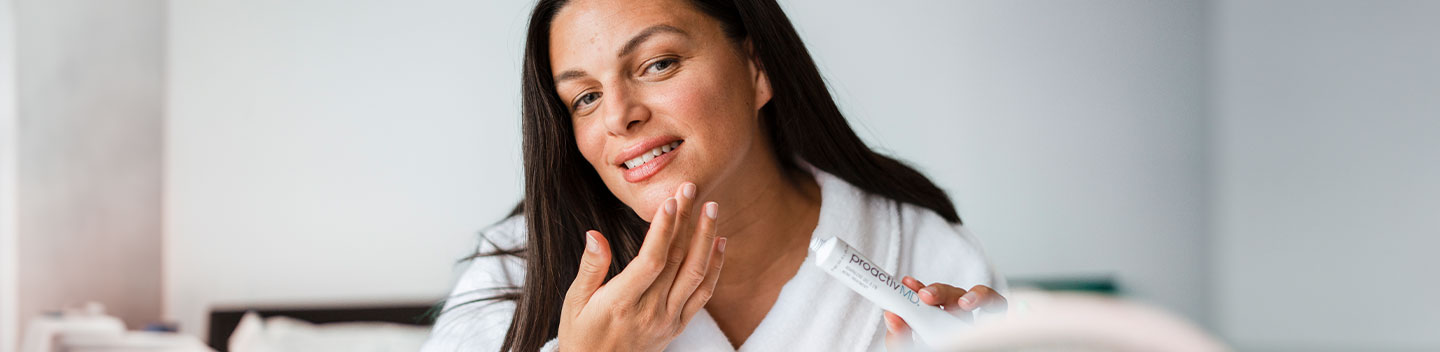 Female applying acne medication on face.